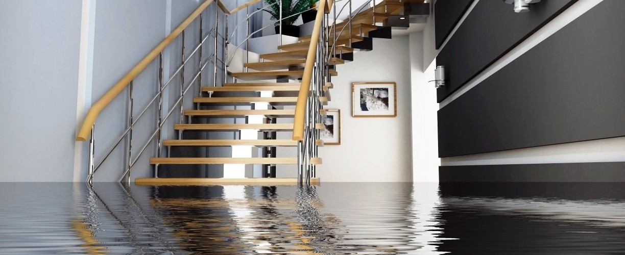 A modern staircase partially submerged in water inside a home.