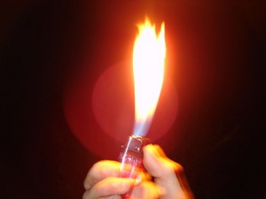 Hand holding lighter with large flame.