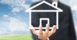 Hand holding virtual house icon outdoors.